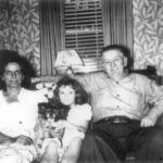 Gilbert Durie on sofa with woman, young girl, and dog